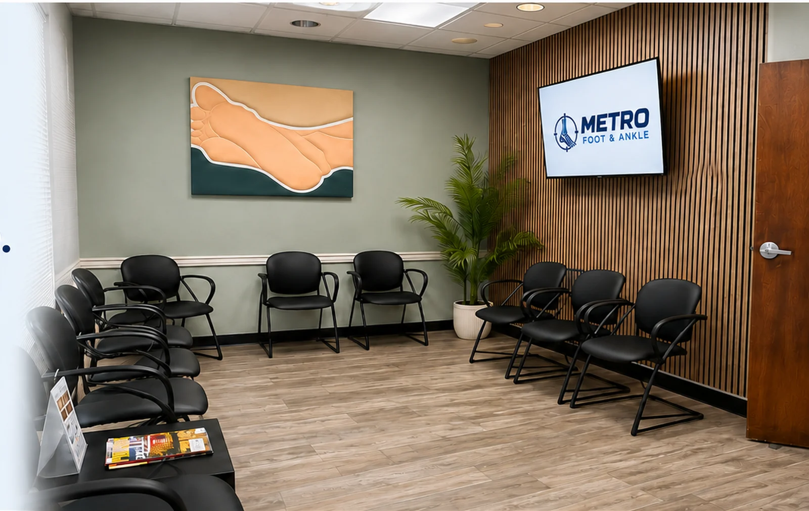 Metro Foot & Ankle office interior in Tempe with seating, a wood slat feature wall, foot artwork, a plant, and a wall display showing the Metro Foot & Ankle logo
